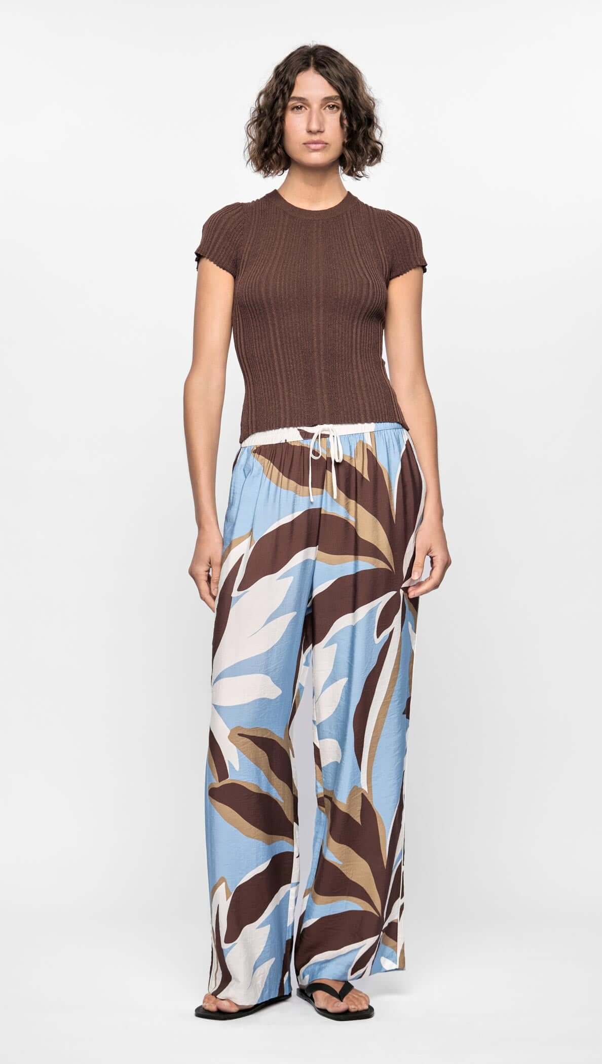 Model wearing Maeve Relaxed Pants with abstract brown, blue, and cream print and elasticated drawstring waist.