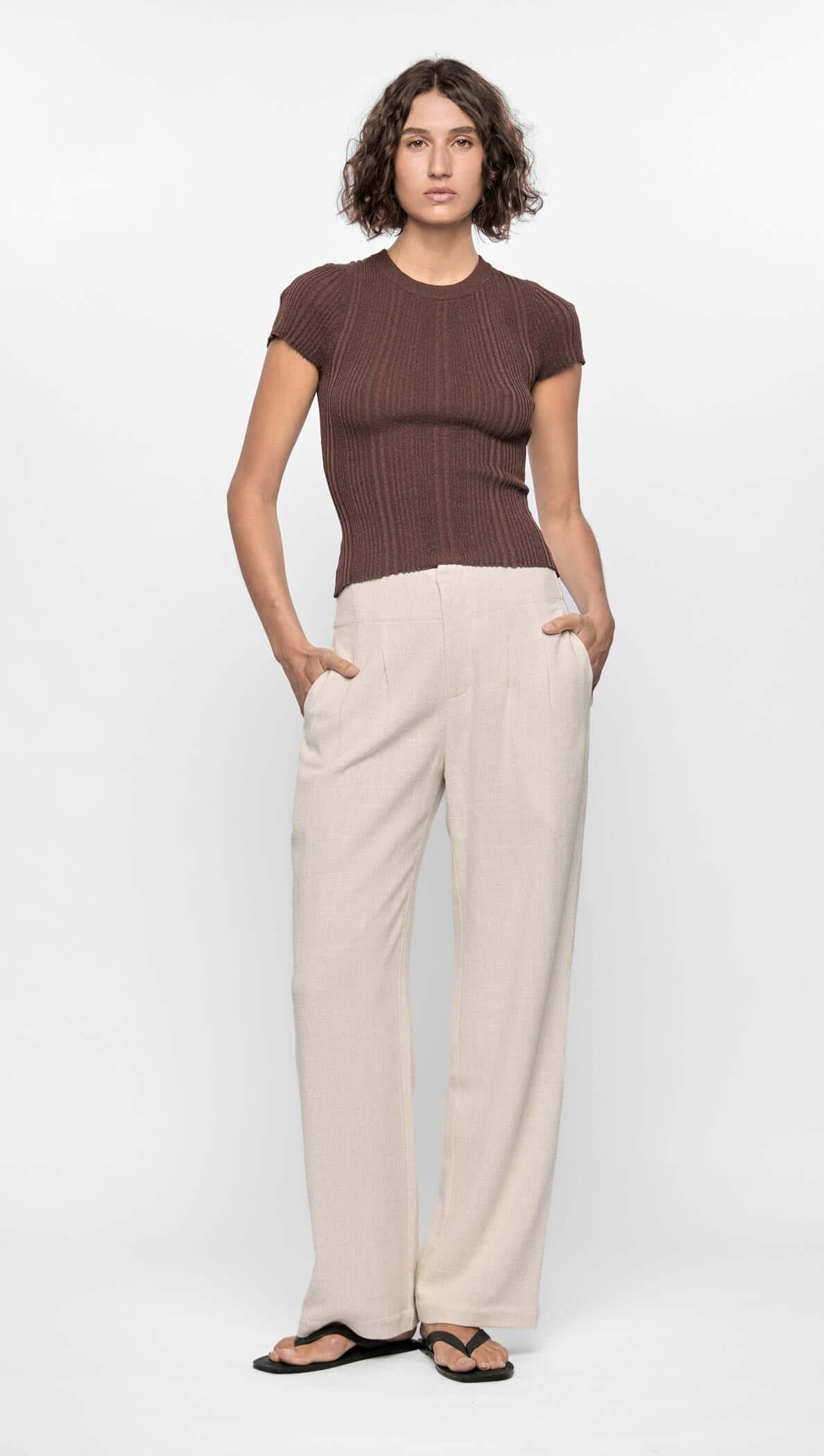 Model wearing the Maya Ribbed Knit Tee in rich chocolate brown, paired with light wide-leg pants for a minimal look.