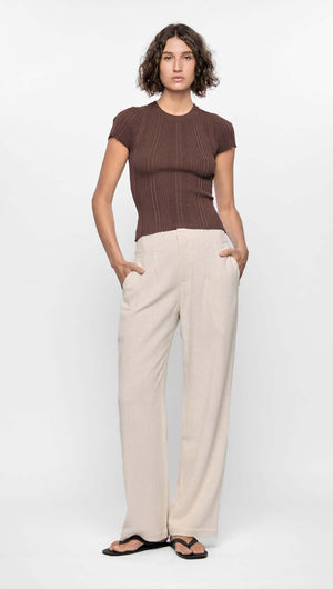 Model wearing the Maya Ribbed Knit Tee in rich chocolate brown, paired with light wide-leg pants for a minimal look.