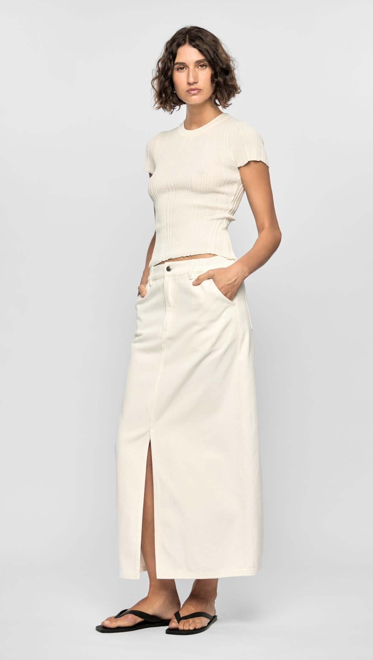 Model wearing the Emmie Denim Midi Skirt in off-white with a high waist, front split, and back pockets.