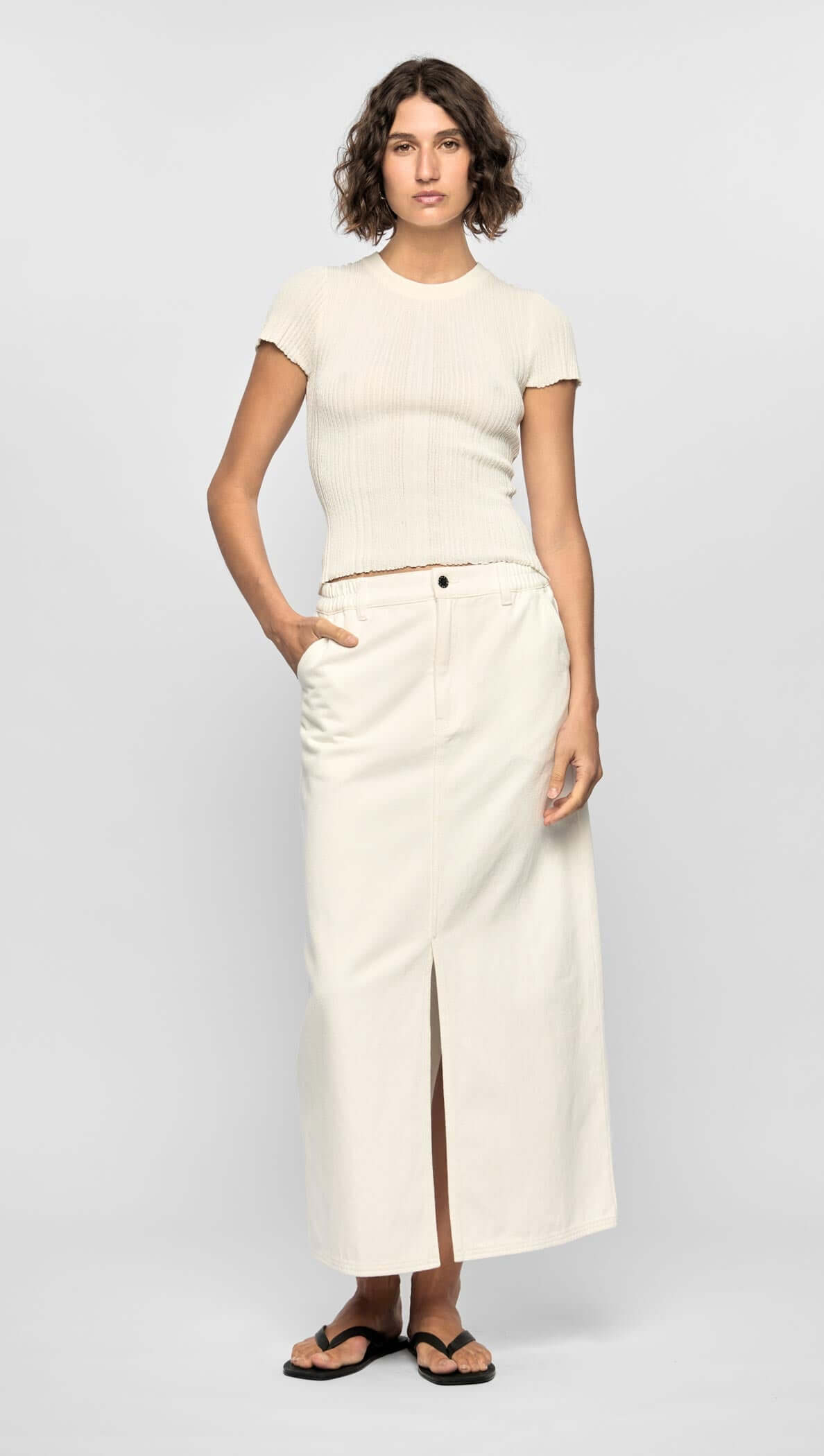 Model wearing the Emmie Denim Midi Skirt in off-white, featuring a high waist and front split for a modern minimalist look.