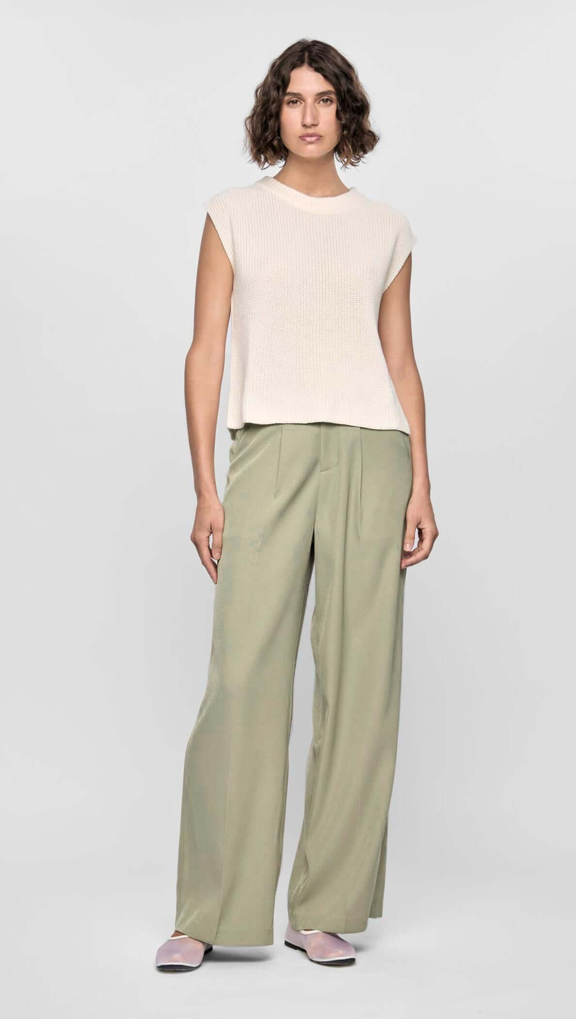Model wearing neutral top with relaxed high-waisted green wide leg pants showcasing modern style and comfort.