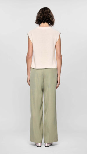 Model wearing neutral beige top and relaxed wide-leg green pants from behind, showcasing a modern, comfortable style.