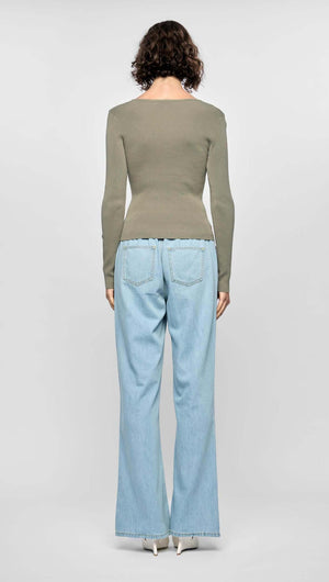 Model wearing the Mira Twist Knit Top in khaki with flared denim jeans from the back, showcasing a fitted silhouette.