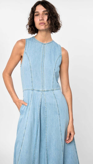Model wearing the Amelia Chambray Midi Dress in light blue, showcasing sleeveless design, panelled fit, and side pockets.