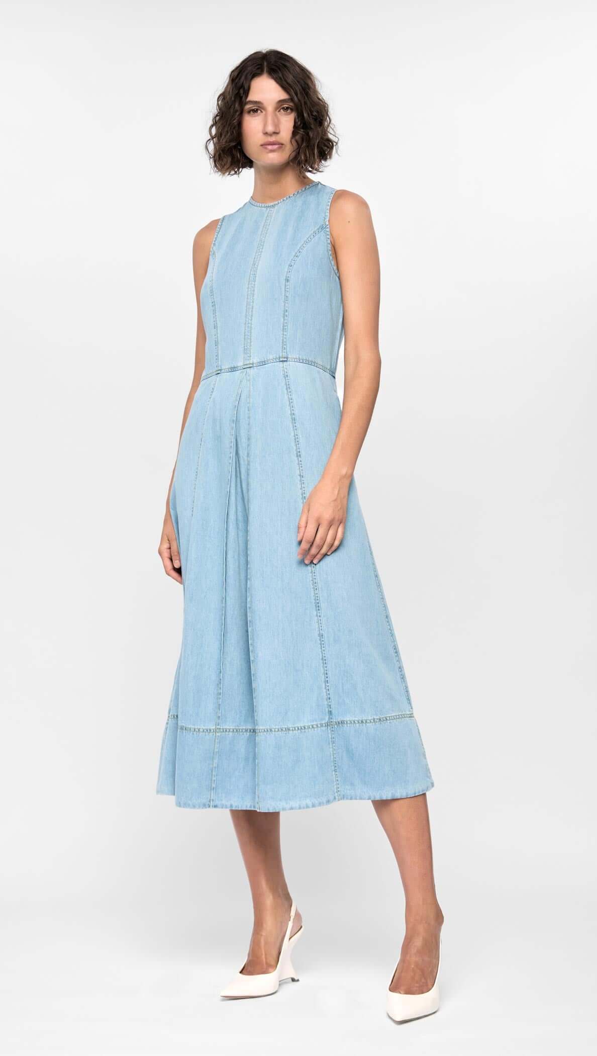 Model wearing the Amelia Chambray Midi Dress in light blue, featuring a fitted bodice and softly flared midi-length hem.
