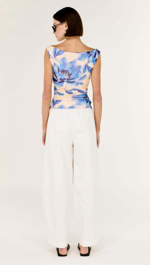 Model wearing a Blue Blurred Floral Mesh Top paired with white pants, showcasing its flattering fit and floral design.