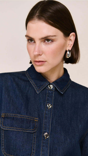 Denim Cropped Short-Sleeve Shirt worn by a model, featuring a structured collar and silver buttons, styled with earrings.