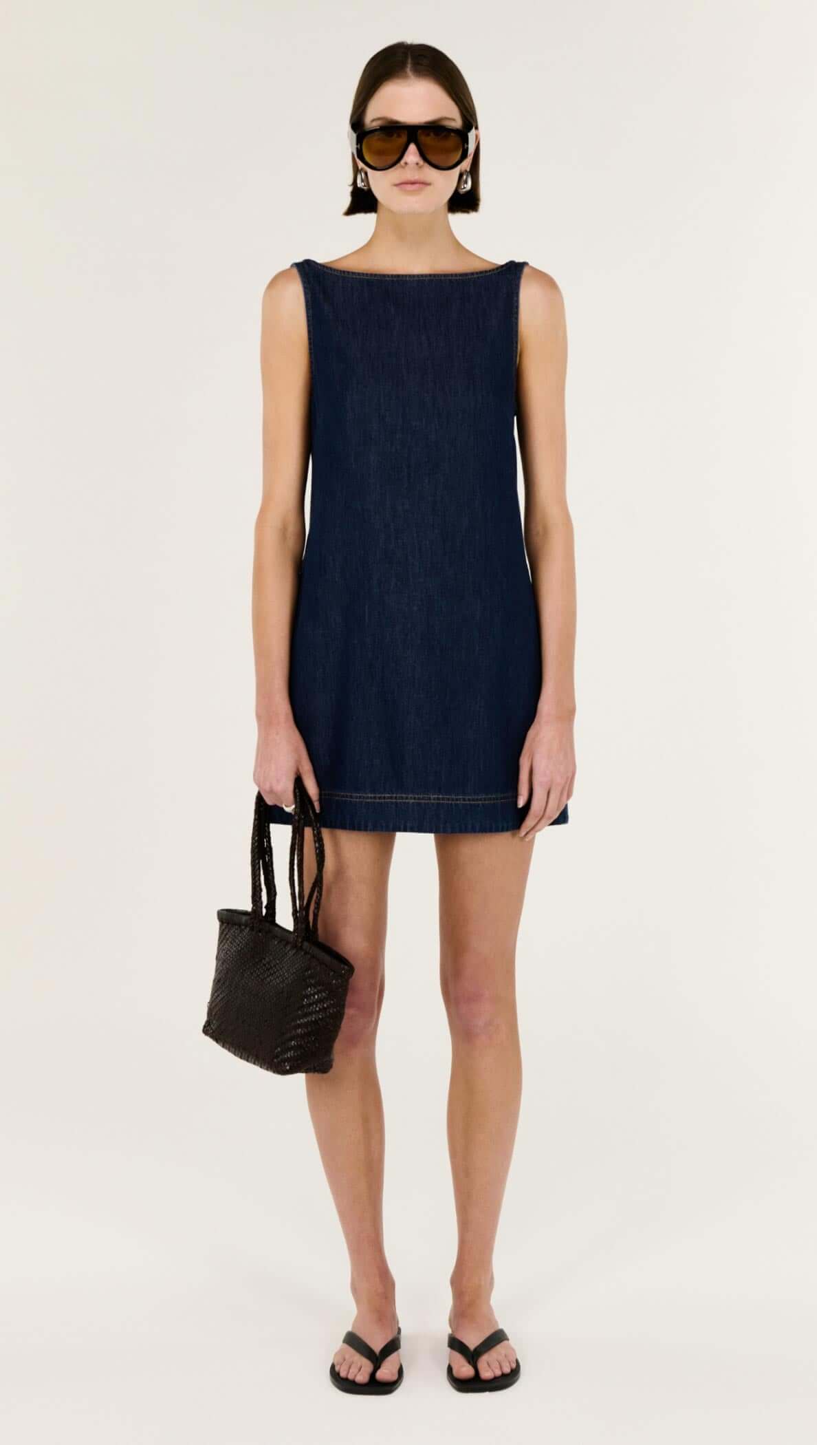 Model wearing Denim Mini Dress with Scoop Back, showcasing a clean A-line silhouette and stylish accessories.