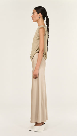 Model showcasing a Champagne Bias Cut Satin Maxi Skirt, featuring a side profile view in a minimalist setting.