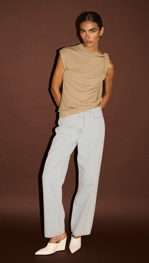 Model wearing Light Wash Straight Leg Denim Jeans paired with a stylish taupe top and white heels on a brown background.