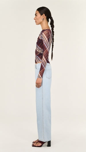 Model wearing a Plaid Mesh Boat Neck Top with Gather Detail paired with high-waisted jeans, showcasing a stylish side profile.