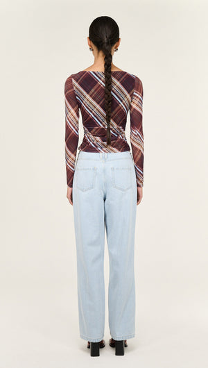 Back view of a model wearing a Plaid Mesh Boat Neck Top with Gather Detail paired with light blue jeans.