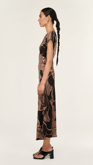 Side view of a model wearing the Abstract Leaf Print Bias Cut Midi Dress, showcasing its elegant design and flow.