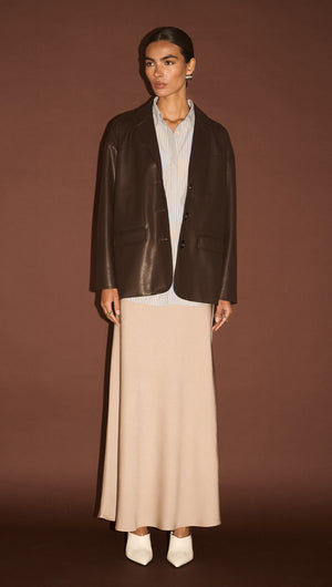Model wearing a Chocolate Relaxed Vegan Leather Blazer over a fitted shirt and long skirt, exuding modern style.
