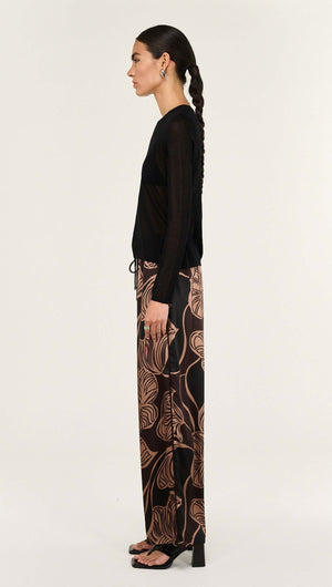 Model wearing Abstract Leaf Print Relaxed Silky Pants with a black top, showcasing a stylish side view.