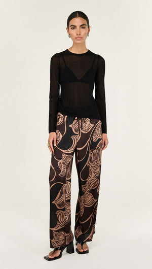 Model wearing Abstract Leaf Print Relaxed Silky Pants paired with a sheer black top and stylish footwear.