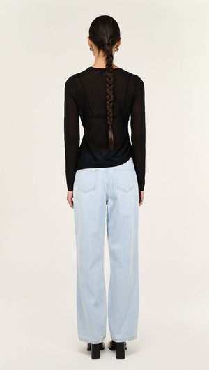 Model wearing Black Ruched Detail Sheer Knit Top paired with light blue jeans, showcasing a stylish back view.
