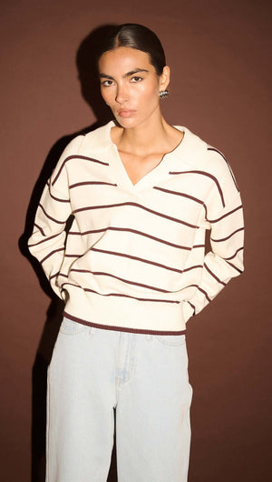 Model wearing a Chocolate Stripe Polo Knit Jumper with a relaxed fit against a brown background.