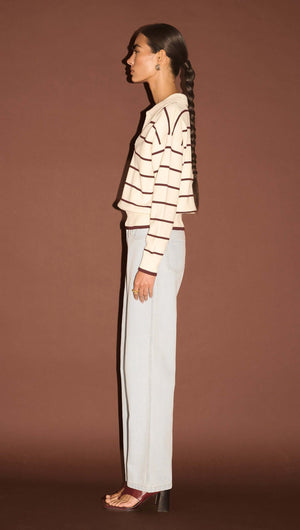 Model showcasing the Chocolate Stripe Polo Knit Jumper in a side view against a brown background.