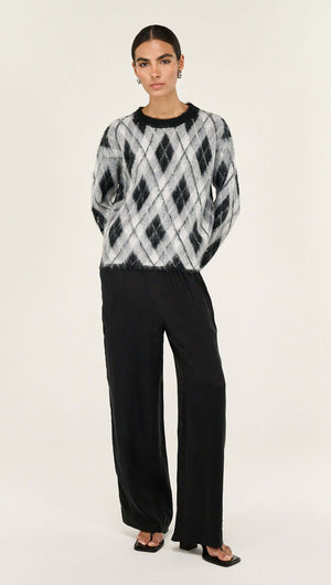 Model wearing a Relaxed Fit Argyle Brushed Jumper with black wide-leg pants, showcasing a stylish and cozy look.