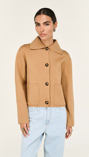 A model wearing a Caramel Knitted Barn Jacket with a collar and button-down front, styled with light blue jeans.