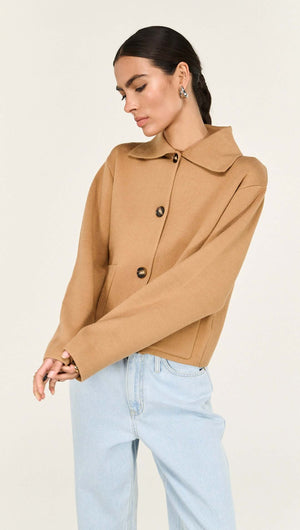 Model wearing a Caramel Knitted Barn Jacket featuring a stylish collar and buttons, paired with blue jeans.