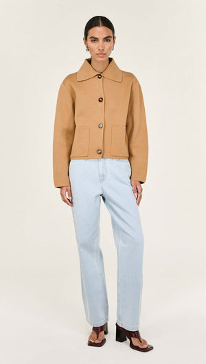 Woman wearing a Caramel Knitted Barn Jacket paired with light blue jeans, modern style and soft texture.