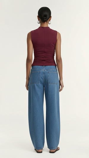 Model wearing Burgundy High Neck Ruched Jersey Top with wide-leg jeans from the back view.