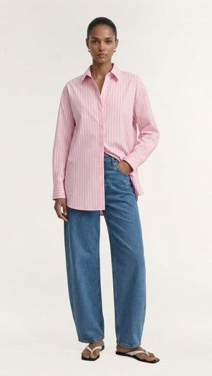Model wearing an Oversized Cotton Shirt with Back Button Detail, styled with blue jeans and flip-flops.