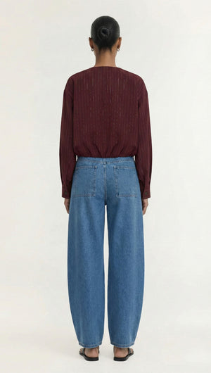 Back view of a model wearing a Burgundy Pinstripe Cropped Jacket with blue wide-leg jeans.