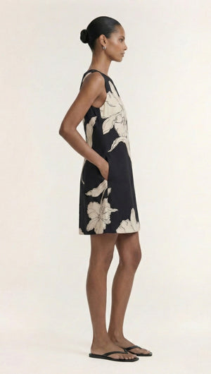 Model wearing a Sketched Floral Sleeveless Mini Dress with pockets, showcasing a side view of the dress's elegant design.
