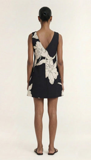 Back view of a model wearing a Sketched Floral Sleeveless Mini Dress with a V-neck design and floral patterns.