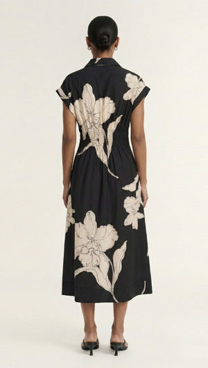 Back view of a woman wearing a Cream Floral Midi Shirt Dress with a black background and large floral prints.