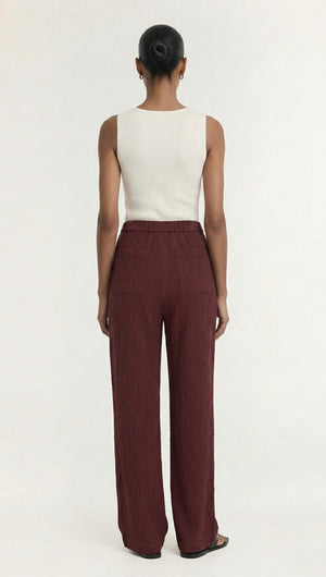 Model showcasing the back view of Textured Burgundy Relaxed Fit Pant paired with a simple white top.