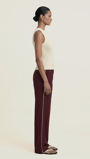 Model wearing a Burgundy Pinstripe Relaxed Pant with a cream sleeveless top, showcasing a side view of the outfit.