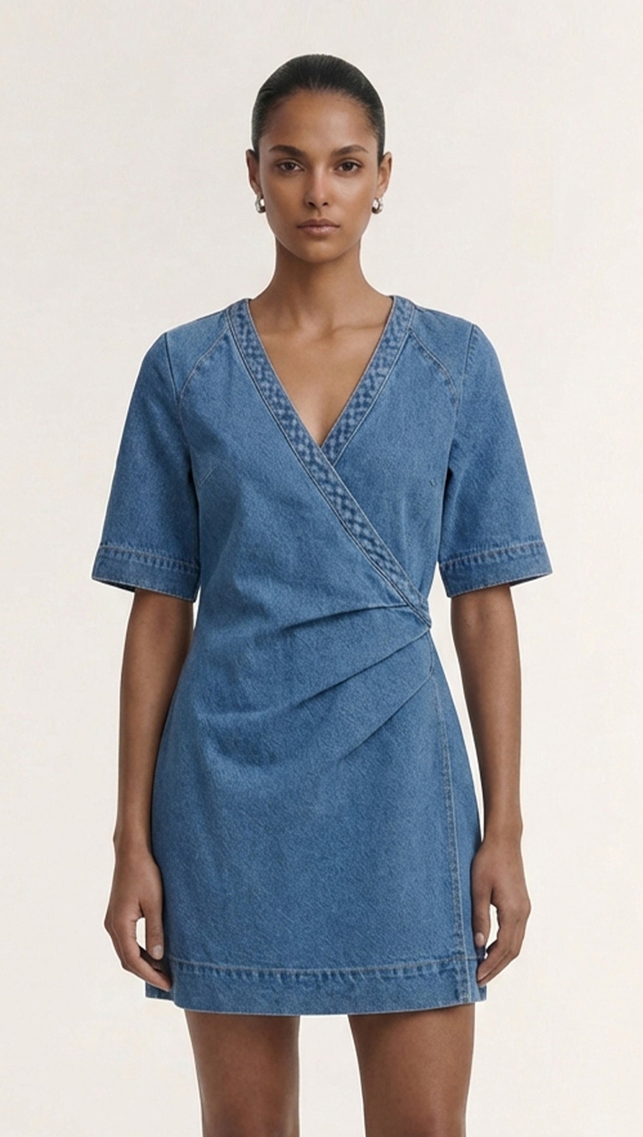 Model wearing a Cotton Denim Wrap Detail Mini Dress, showcasing its refined design and feminine silhouette with short sleeves.