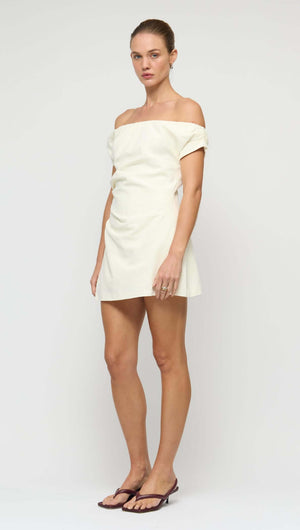 Linen Blend White Off-Shoulder Mini Dress worn by model, showcasing its fitted design and off-shoulder neckline.