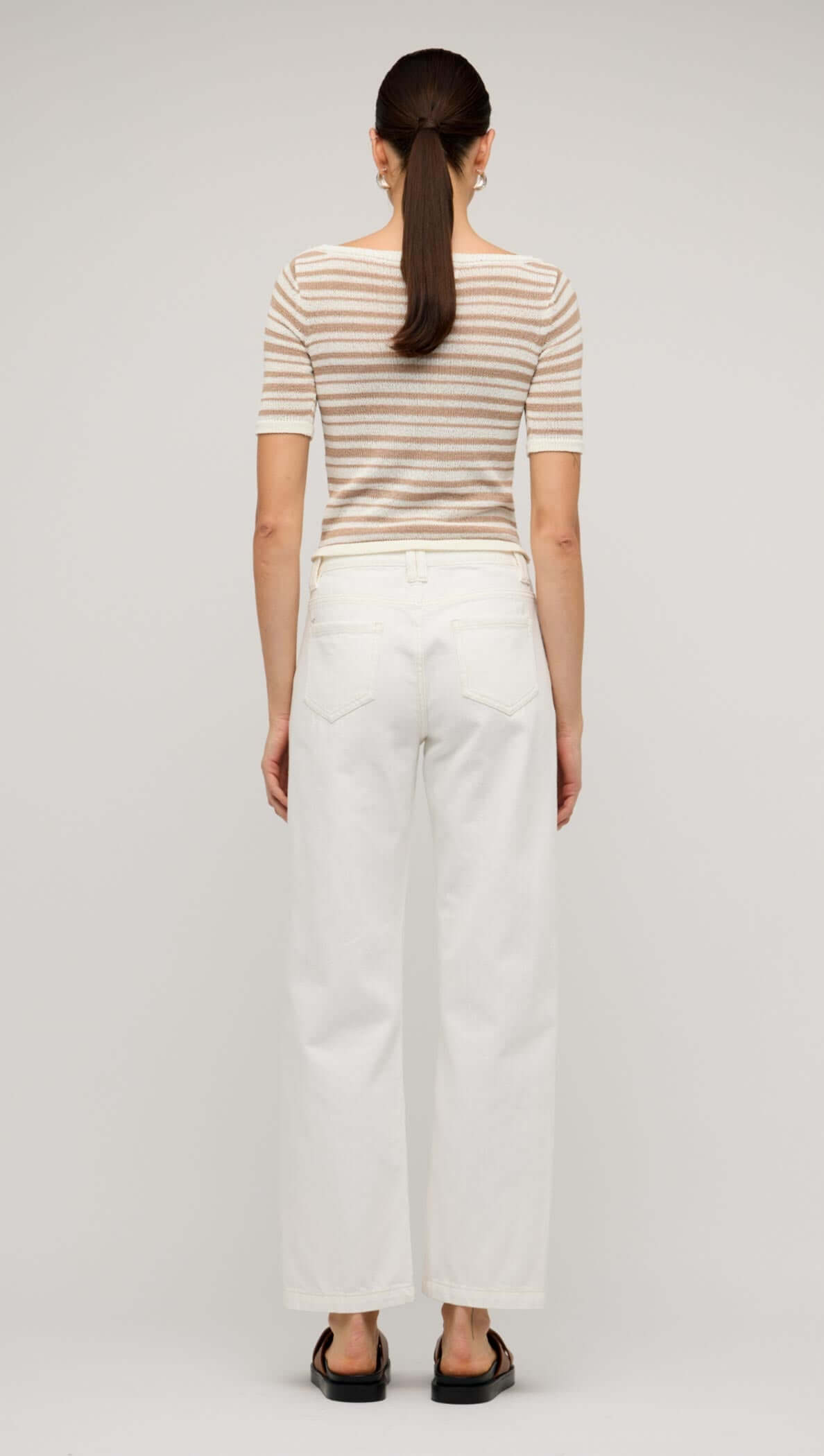 Back view of a woman wearing white denim mid-rise straight jeans and a striped top, showcasing a casual outfit.
