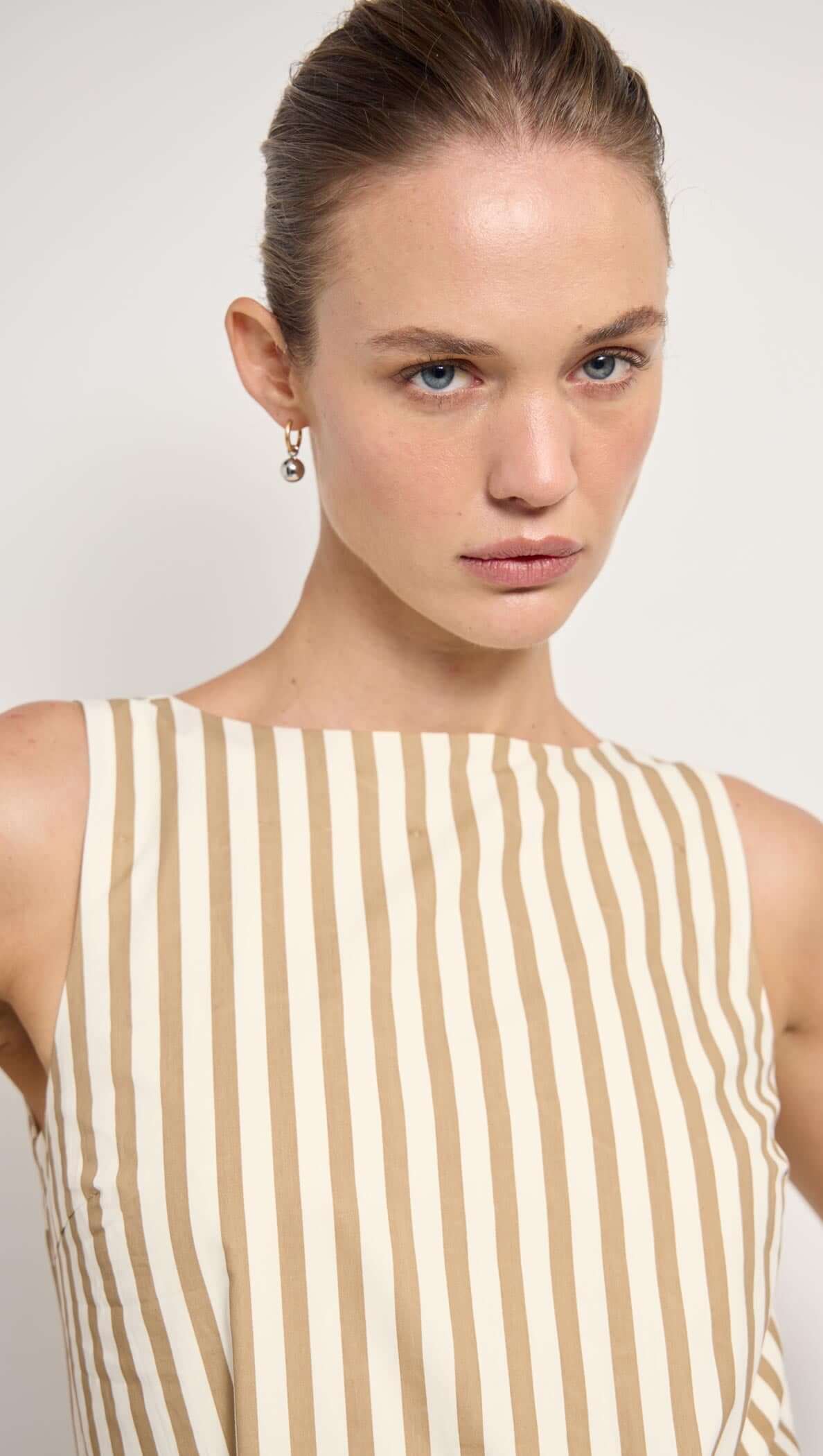 Model wearing a Cotton Stripe Mini Shirt Dress with a relaxed fit and low back, paired with a straw bag.