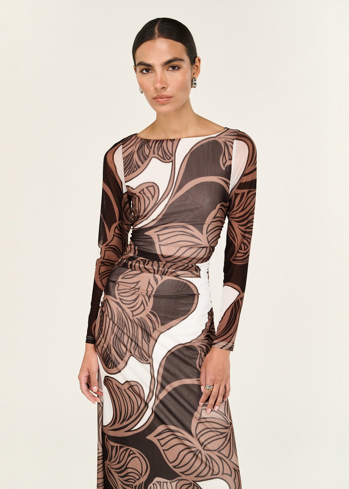 Model wearing Abstract Leaf Print Mesh Midi Dress with a fitted bodice with ruched waist detail and a boat neckline, turned to the side.