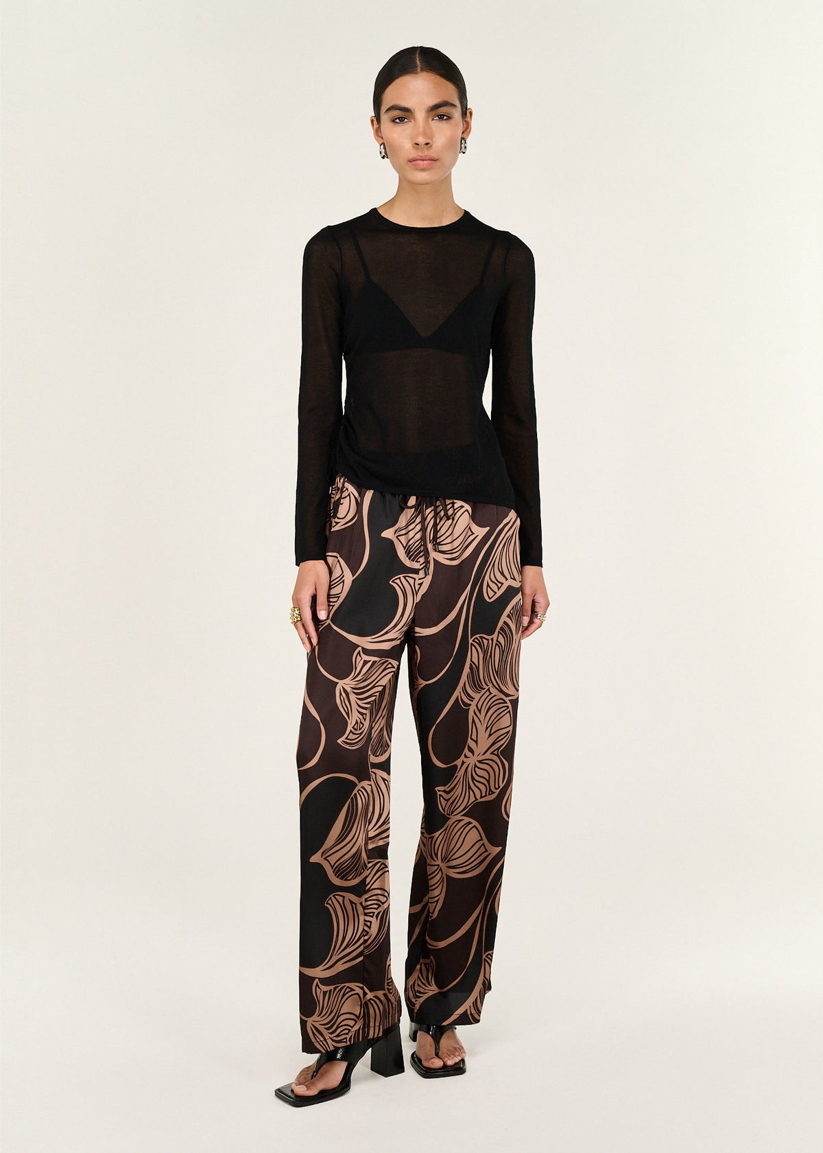 Model wearing Abstract Leaf Print Relaxed Silky Pants with an elasticated waistband with drawstring and a full-length silhouette.