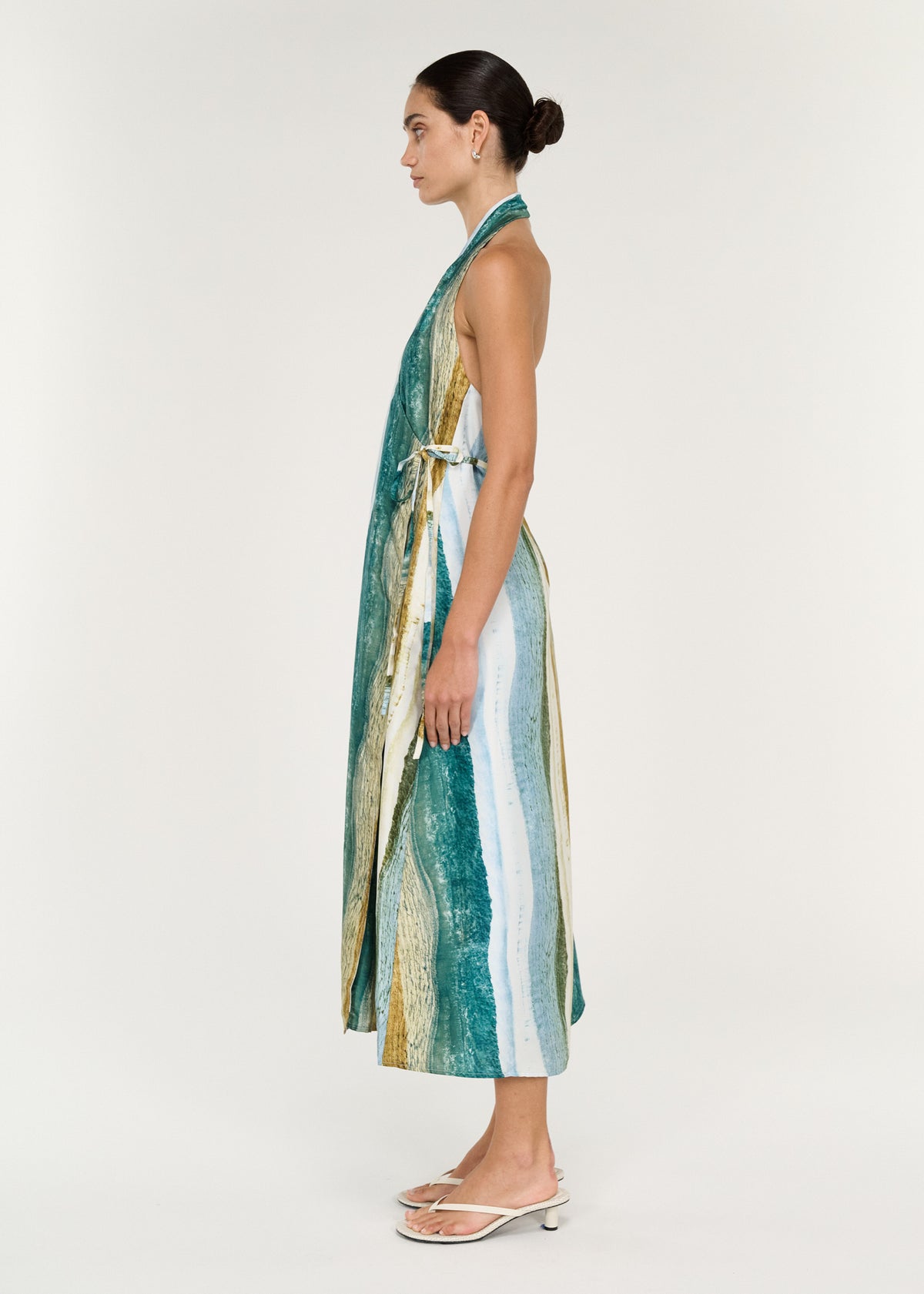 Side view of a model wearing a Wrap Halter Midi Dress in Ocean Tide with an abstract coastal-inspired print.