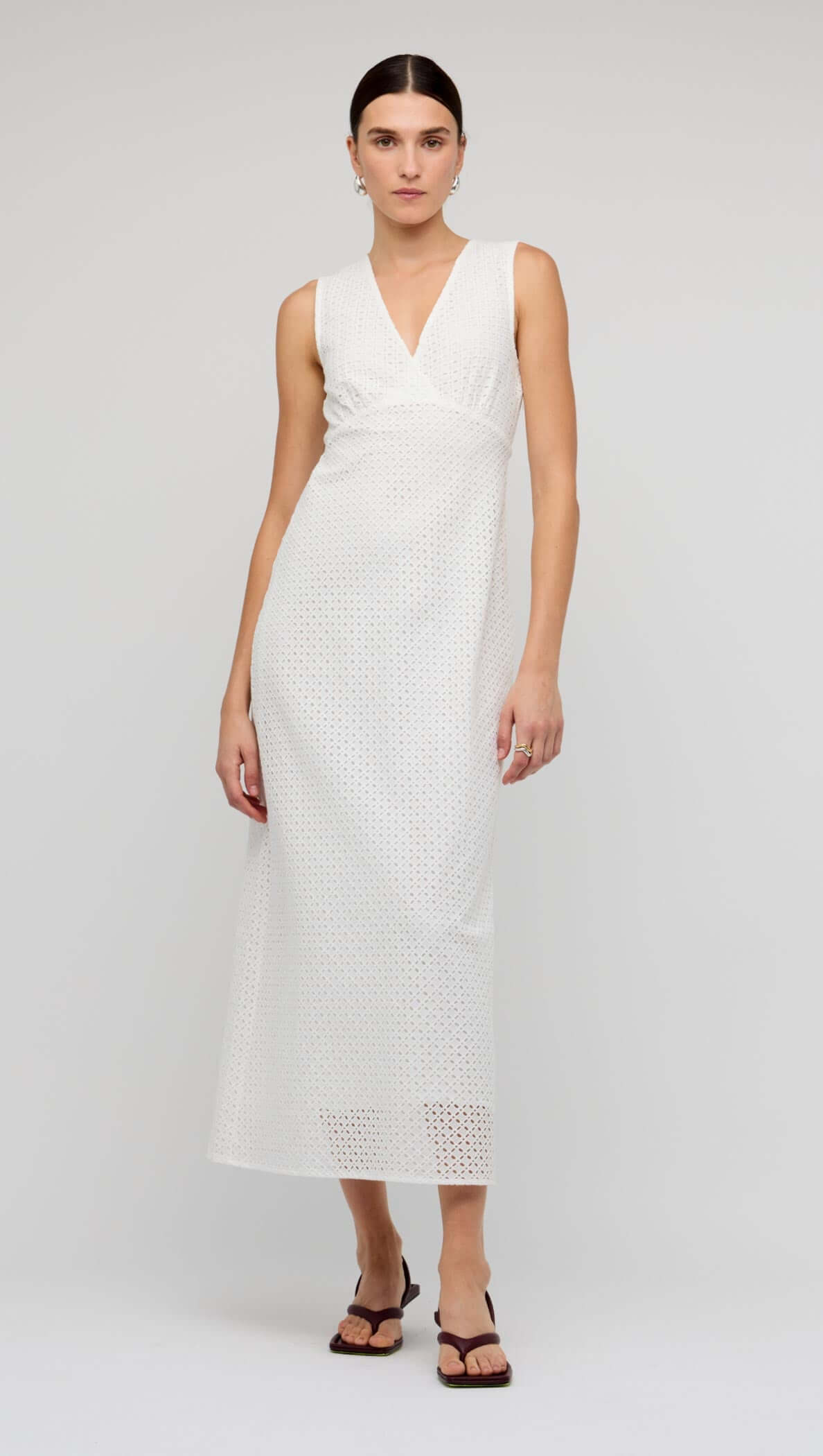 White Broderie Bias Midi Dress displayed on a model, featuring a sleeveless V-neck and broderie detailing.