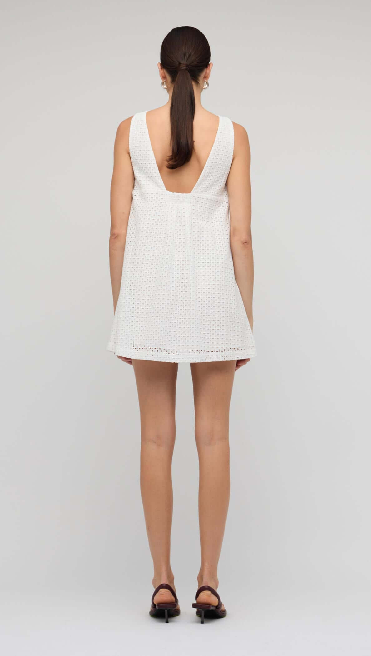Back view of the White Broderie Mini Shift Dress showcasing the deep V-back design and sleeveless style.