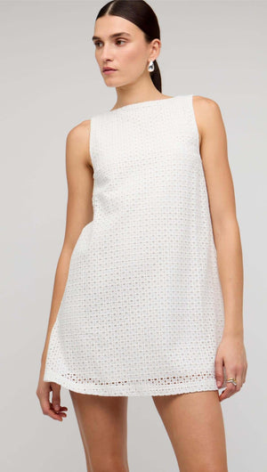 Model wearing a White Broderie Mini Shift Dress by Staple the Label, featuring a sleeveless design and deep V-back.