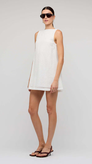 Model wearing a White Broderie Mini Shift Dress by Staple the Label with sunglasses and stylish sandals.