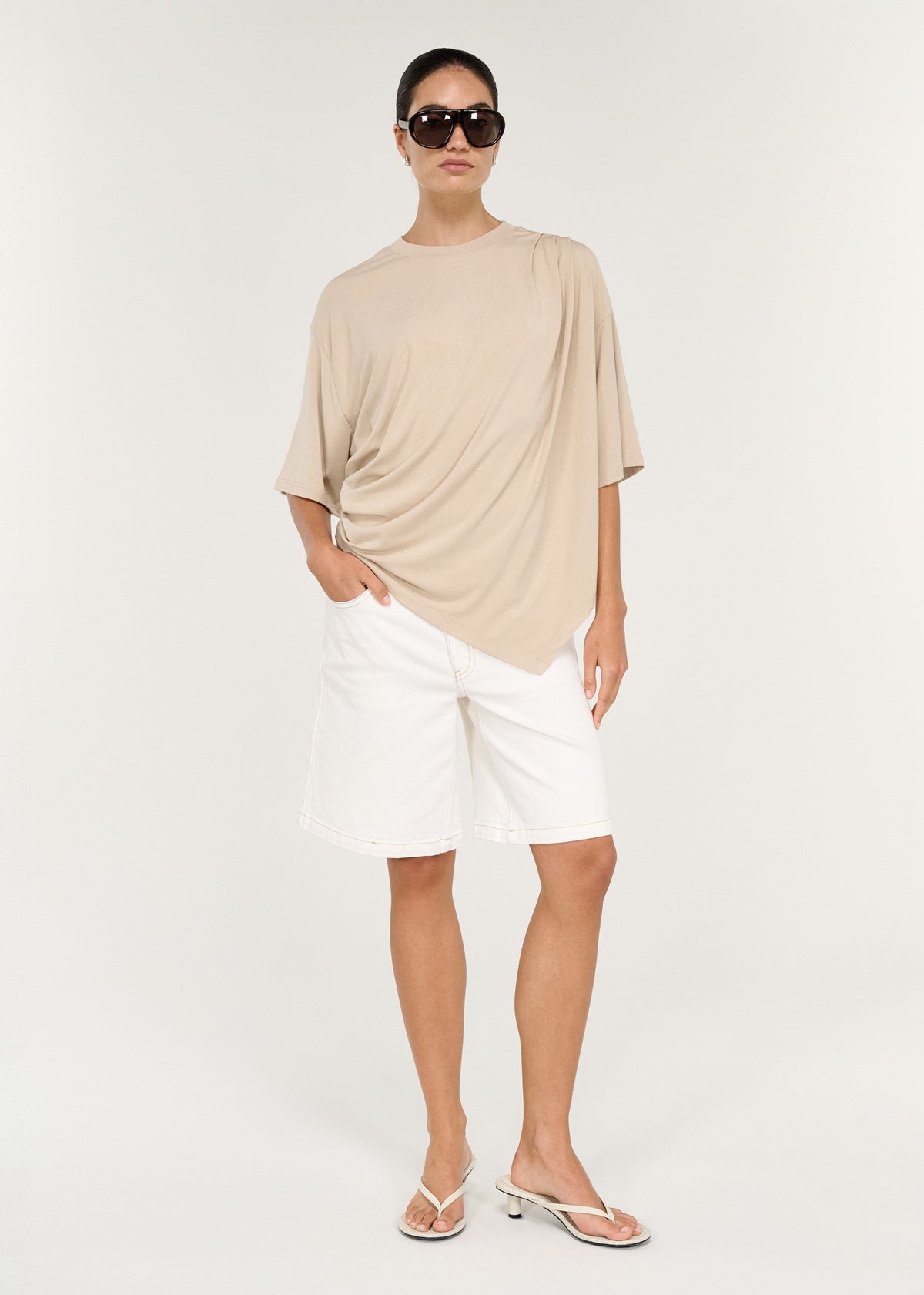 Model wearing Asymmetric Draped Oversize Tee in Beige, showing a soft fluid jersey fabrication and an oversized silhouette.