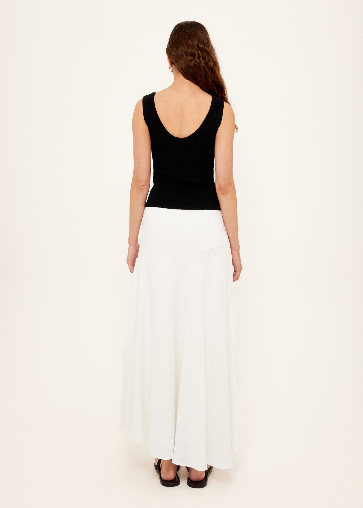 Back view of the Asymmetric White Bias Maxi Skirt with an invisible side zip closure and an asymmetric waistband detail.