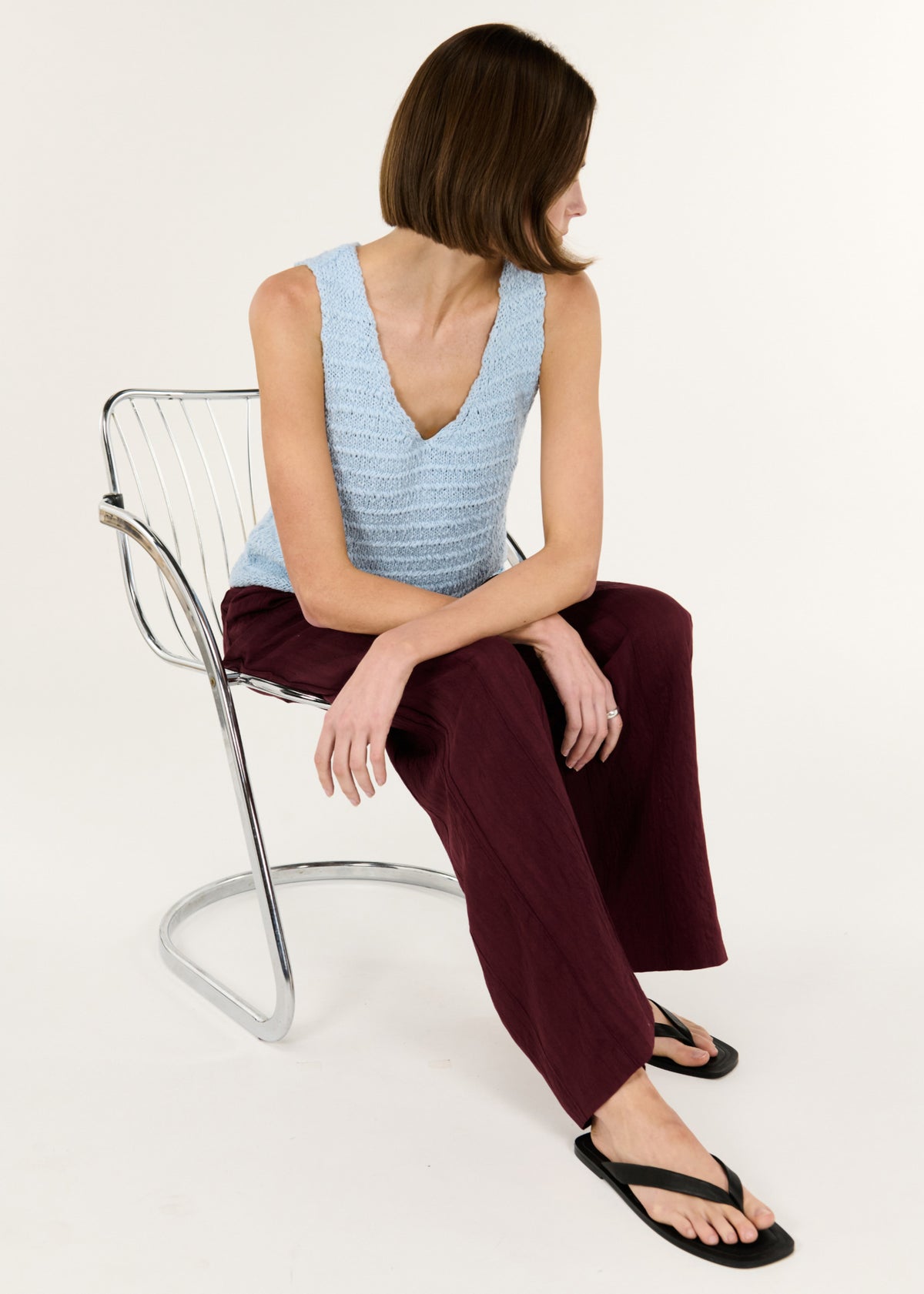 Model seated wearing Baby Blue Cotton Knit Tank with a sleeveless cut and a flattering V neckline.
